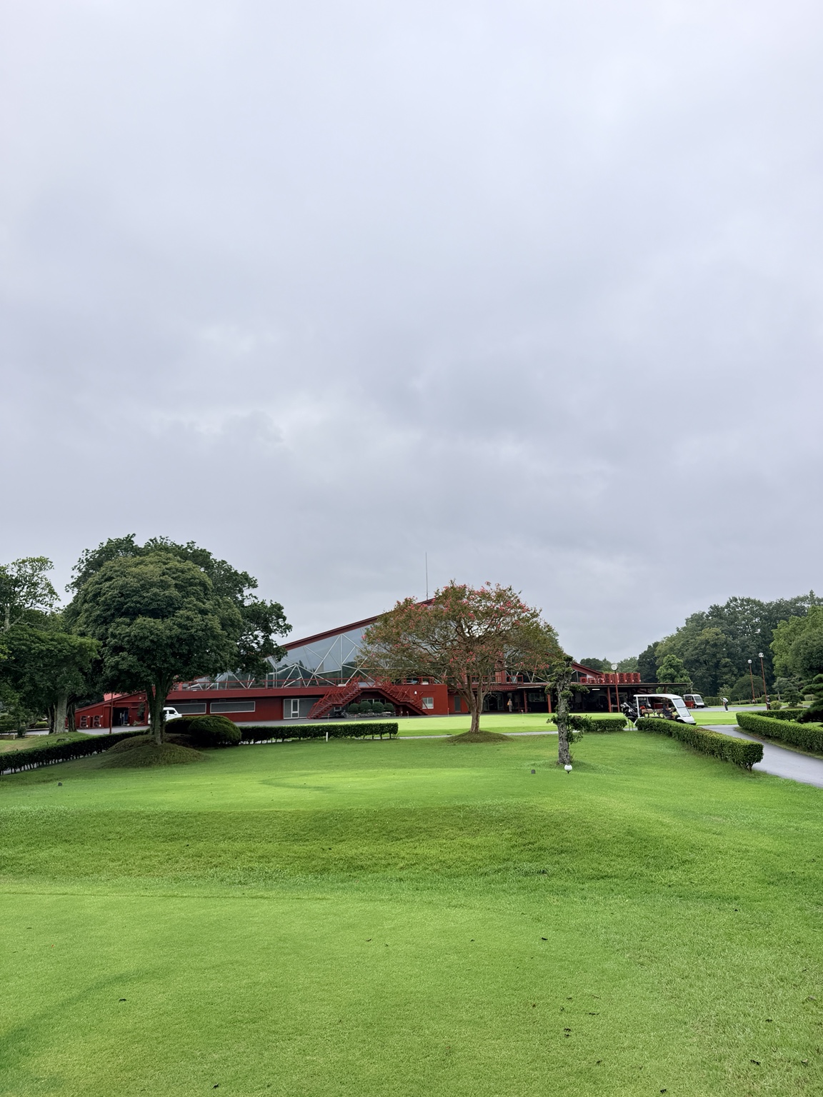 愛媛ゴルフ倶楽部・內子球場｜紅色會館、玻璃立面與前方草地。